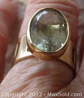 Top view of ring on finger showing faceted green amethyst and bezel setting