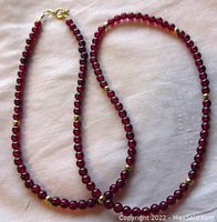 Full view of the garnet bead necklace with gold filled beads and clasp laid out flat.