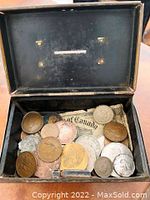 Photo showing inside of the old metal box with assorted coins and paper items