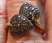 Close-up front view of sterling silver ring showing two leaf shapes densely set with diamonds.