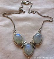 Front view of necklace showing three oval moonstone cabochons and curb link chain.