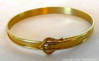 Front view of the vintage 10K gold filled child’s bangle showing its shiny finish and buckle design.