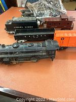 Overview showing locomotive, tender, two black gondolas, orange boxcar, brown caboose and track bundle