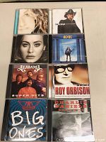 Eight CDs arranged in two columns, including albums by Celine Dion, Tim McGraw, Adele, AC/DC, Alabama, Roy Orbison, Aerosmith, and Charlie Daniels.