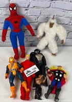 Full shot of all six figures standing against white brick wall.