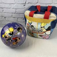 Purple bowling ball with Powerpuff Girls graphics and blue/red/white and yellow themed Cartoon Network bowling bag with various cartoon characters.