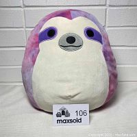 Front view of a 12-inch Squishmallow sloth plush toy showing its tie-dye purple and pink pattern with white face and belly.