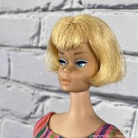 Front three-quarter view of doll head and shoulders showing hairstyle, eye makeup and swimsuit neckline.