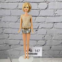 Front view of vintage Casey Barbie doll with blonde hair, woven top, silver shorts, and gold belt.