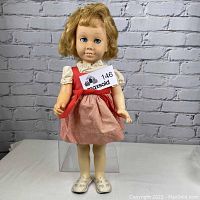 Front view of vintage Chatty Cathy doll wearing a red and white striped dress showing its blonde curly hair and blue eyes.