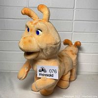 Front-angle view of Grubby, the plush caterpillar, showing facial features and front legs.