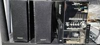 Photo showing Panasonic stereo system with CD player, cassette tape deck, control buttons and volume knob on the front panel, alongside two matching Panasonic speakers.