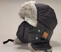 Black fuzzy winter hat with faux fur lining and detachable fleece lined mask, shown on mannequin side profile.