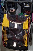 Front view showing transparent curved rain cover and yellow-black fabric front panel with reflective patch.