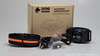 Photo shows Dog Range Smart No Shock Dog Bark Control Collar with black and orange nylon collar, charging cable, USB connector, additional small accessories inside a plastic bag, and the product box with branding and product illustration.