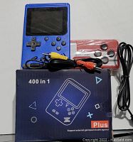 Blue handheld game console with attached AV cables and an external red and white game controller. Package shows '400 in 1 Plus' branding.