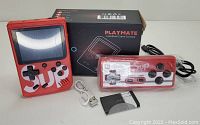 Photo of red Playmate handheld game console with screen, wired controller, USB charging cable, instruction manual, and original box.