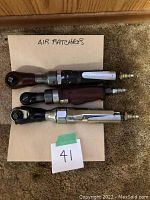 Top view of three 3/8" drive air ratchets placed on cardboard with label 'AIR RATCHETS' showing details and condition with one end air hose connectors visible.
