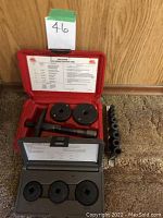Red and gray plastic cases containing disc brake caliper tool components including piston adapters and threaded rewind tool