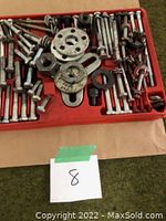 Top view of red plastic tray containing gear puller and steering wheel puller components with bolts and attachments.