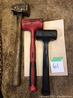 Three mallets side by side on carpet, showing wooden, red rubber, and black plastic mallets