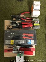 Overall view showing multiple hand tools with red handles including pliers, riveter, clamps, screwdriver, and rivet boxes