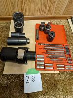 Full lot view showing large socket wrenches, socket adapters, and red plastic case with drill bits and extractors.