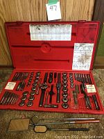 Red plastic case open displaying taps, dies and accessories arranged in molded slots