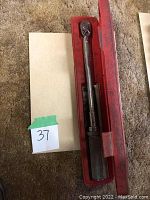 Torque wrench seated in red case, knurled handle visible