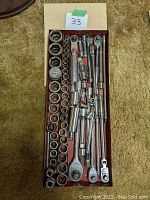 Overhead view of tray containing sockets arranged in rows on left and ratchet handles, extensions and adapters on right