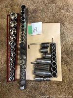 Photo showing multiple socket pieces organized in two metal rails and various loose socket tools.