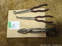Two spark plug wire removers and one pair of tin snips on a beige surface