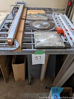 Top-down view of saw table showing fence, spare blades, manual, rails, hardware box