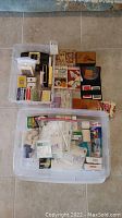 Top-down view of all items in two plastic storage bins showing Bridge card game supplies and first aid supplies arranged separately.