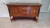 Front view of buffet sideboard showing decorative veneers, cabinet doors, drawer and open shelf