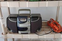 Completed view of Phillips portable CD micro system with two speakers and orange extension cord placed beside it.