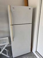 Front view of a white Roper refrigerator with two doors, top freezer and bottom fridge compartments. The surface shows dirt and signs of wear.