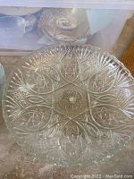 Clear pressed glass decorative plate showing star and floral patterns in detail.