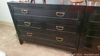 Front view of the black four-drawer Baker dresser showing overall design and brass handles