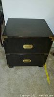 Front view of vintage dark wood Baker nightstand showing two drawers with brass recessed handles and brass corner accents.