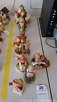 Eight Hummel figurines arranged in a line on a table showing size and detail