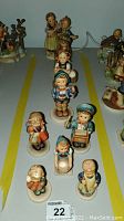 Top view of nine different Hummel figurines grouped on a surface with yellow lines