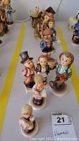 Front view of all 8 Hummel figurines arranged in lines displaying characters and colors