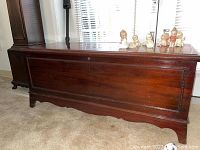 Long front side view showing the entire chest lengthwise and several collectible figurines placed on the top surface.