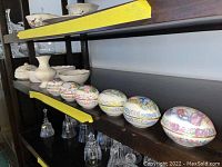 Shelves displaying the Lenox eggs, bowls, and music box arranged with visible delicate porcelain and gold accents