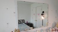 Large beveled wall mirror hanging on wall, reflecting bedroom scene.