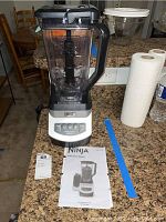 Full view of Ninja Professional Blender assembled with manual laid out in front on countertop with kitchen background.