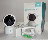 HeimVision HM203 HD Smart WiFi camera with power adapter, mounting hardware, and product box displayed on a white surface.