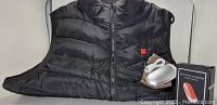 Black Genovega heated vest laid flat with power pack and manual beside it