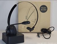 Photo of wireless office headset BH-M97 on charging dock with USB adapter cable and product box in background.